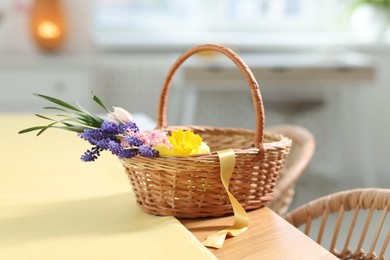 Photo of Wicker basket with beautiful flowers on table indoors
