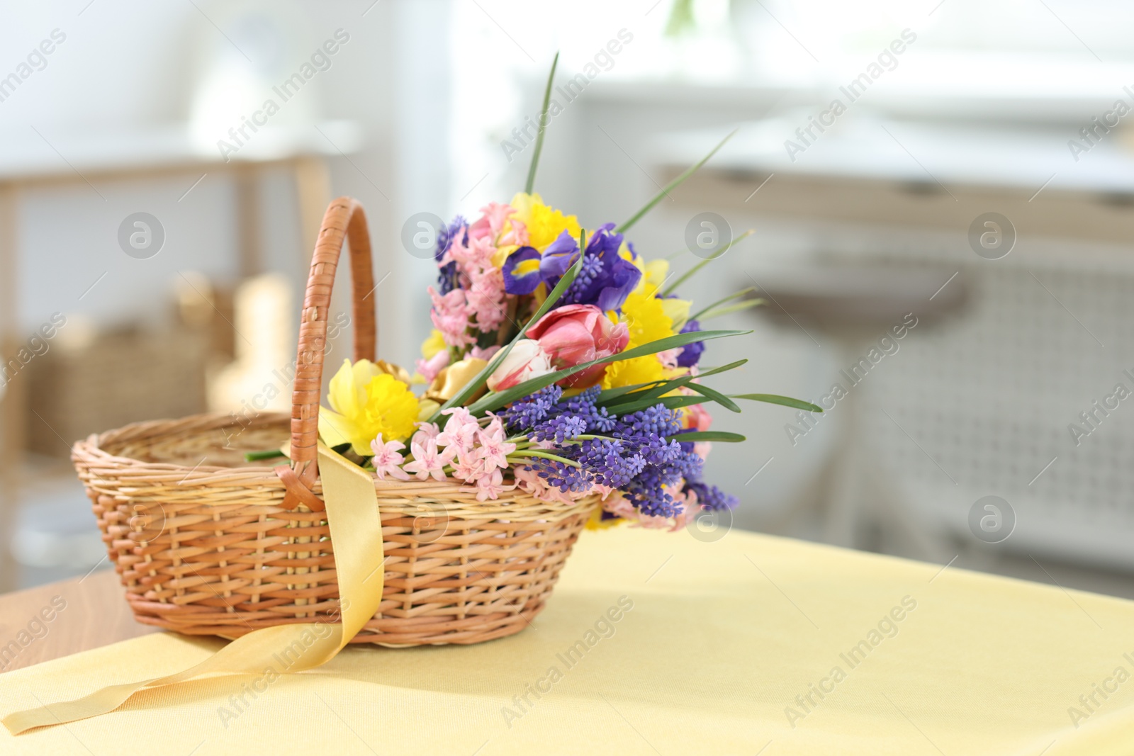 Wicker basket with beautiful flowers on table indoors. Space for text Photo of Wicker basket with beautiful flowers on table indoors. Space for text