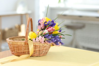 Photo of Wicker basket with beautiful flowers on table indoors. Space for text