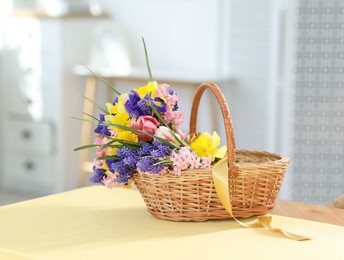 Photo of Wicker basket with beautiful flowers on table indoors