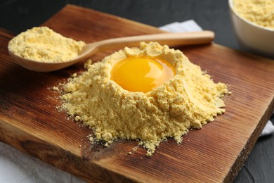 Photo of Corn flour with egg yolk and spoon on table, closeup