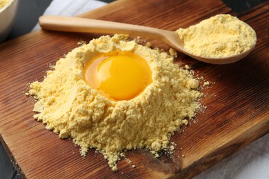 Photo of Corn flour with egg yolk and spoon on table, closeup