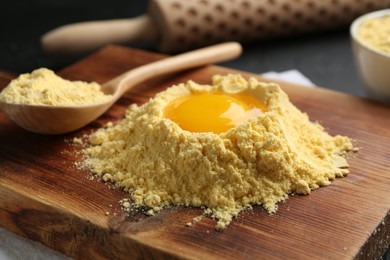 Photo of Corn flour with egg yolk and spoon on table, closeup