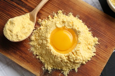 Photo of Corn flour with egg yolk and spoon on table, top view