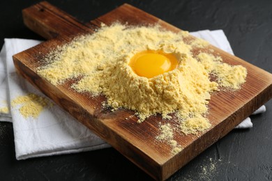 Photo of Corn flour and egg yolk on black textured table, closeup