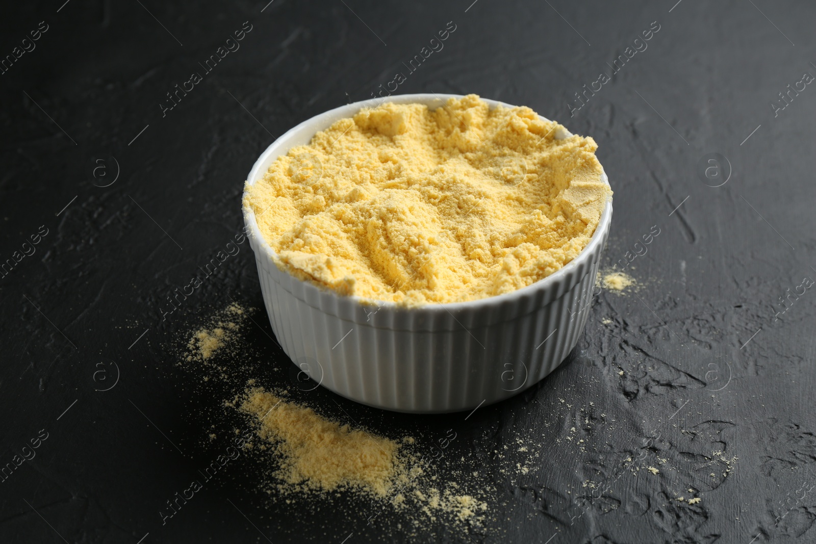 Photo of Corn flour in bowl on black textured table