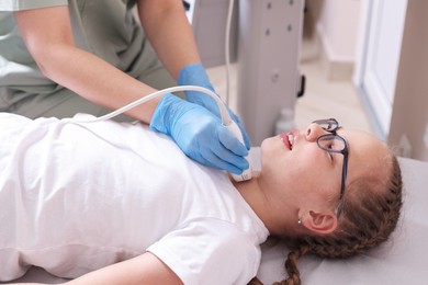 Photo of Sonographer conducting girl's thyroid gland ultrasound examination in clinic, closeup