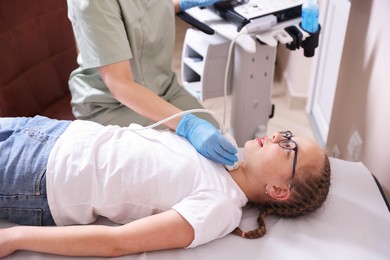 Photo of Sonographer conducting girl's thyroid gland ultrasound examination in clinic, closeup