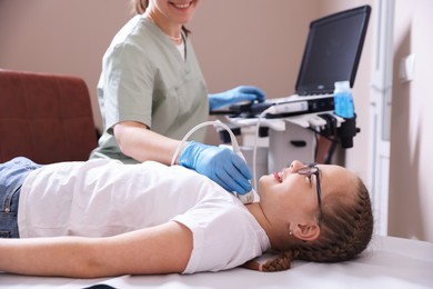Photo of Sonographer conducting girl's thyroid gland ultrasound examination in clinic, closeup
