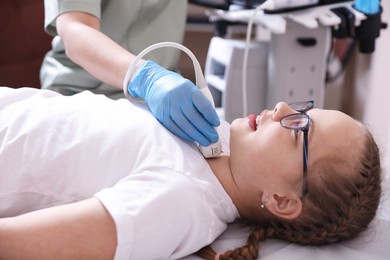 Photo of Sonographer conducting girl's thyroid gland ultrasound examination in clinic, closeup