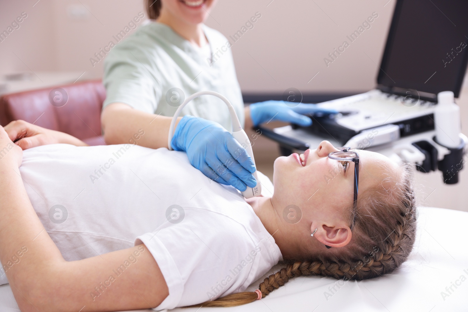 Sonographer conducting girl's thyroid gland ultrasound examination in clinic, closeup Photo of Sonographer conducting girl's thyroid gland ultrasound examination in clinic, closeup