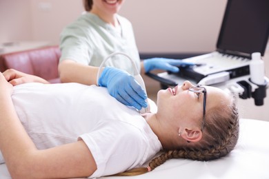 Photo of Sonographer conducting girl's thyroid gland ultrasound examination in clinic, closeup