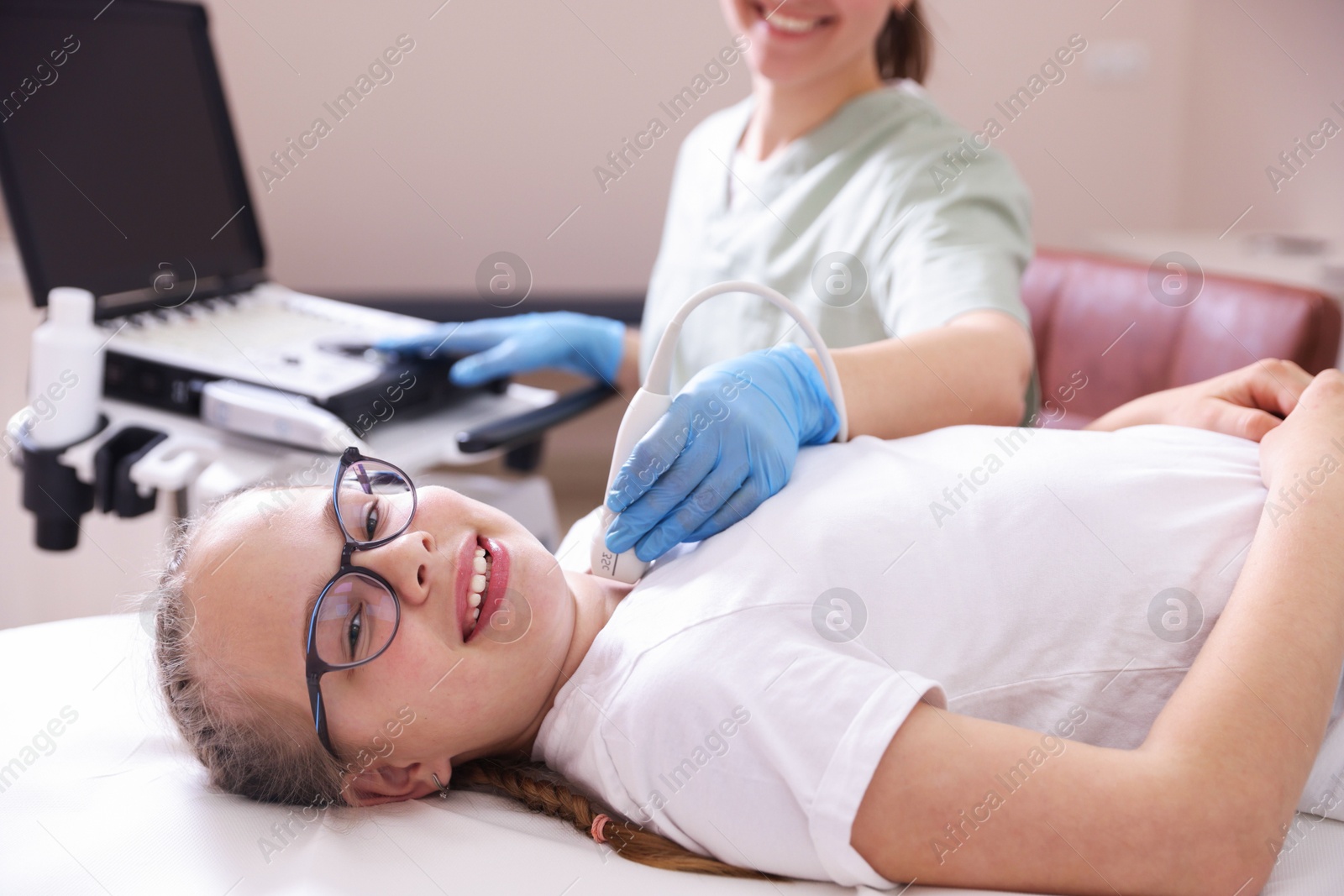 Photo of Sonographer conducting girl's thyroid gland ultrasound examination in clinic, closeup