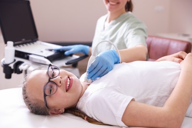 Photo of Sonographer conducting girl's thyroid gland ultrasound examination in clinic, closeup
