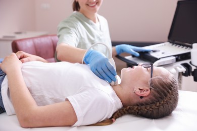 Photo of Sonographer conducting girl's thyroid gland ultrasound examination in clinic, closeup