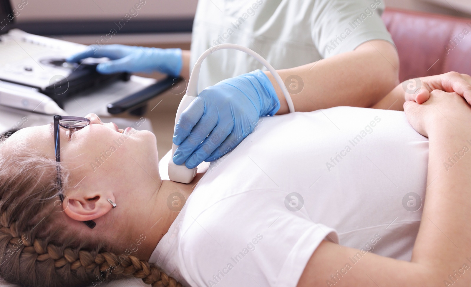 Sonographer conducting girl's thyroid gland ultrasound examination in clinic, closeup Photo of Sonographer conducting girl's thyroid gland ultrasound examination in clinic, closeup