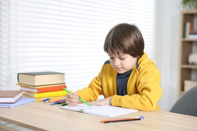 Photo of Cute little boy doing homework at table indoors