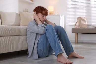 Photo of Teen problems. Depressed teenage boy on floor indoors