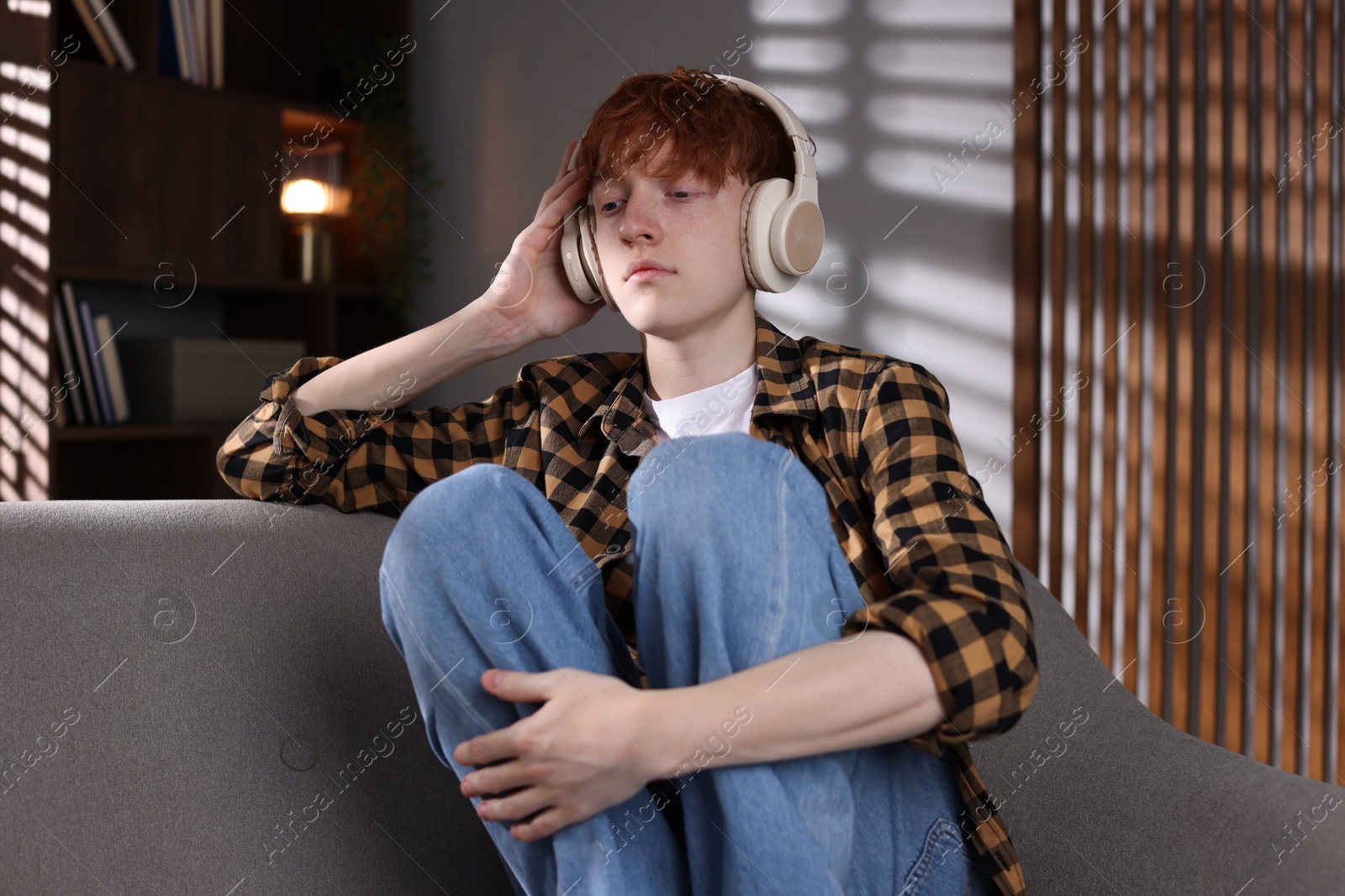 Teen problems. Depressed teenage boy listening to music on sofa at home Photo of Teen problems. Depressed teenage boy listening to music on sofa at home