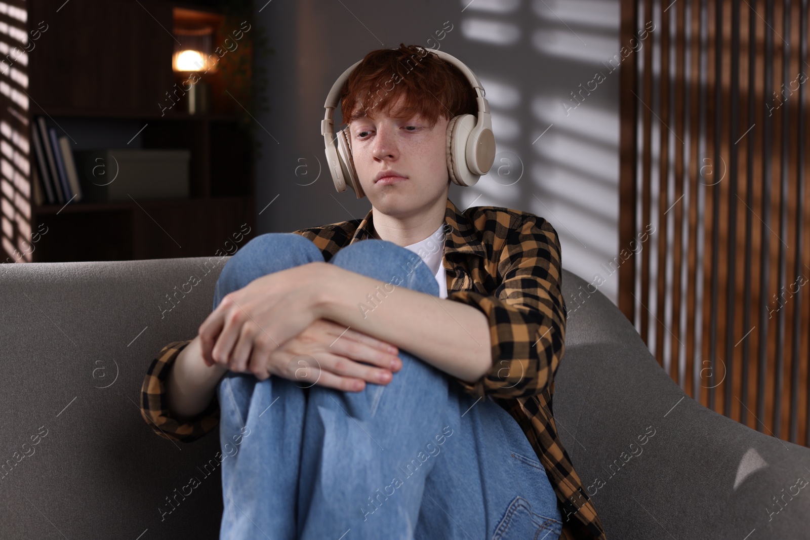 Teen problems. Depressed teenage boy listening to music on sofa at home Photo of Teen problems. Depressed teenage boy listening to music on sofa at home