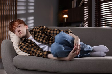 Photo of Teen problems. Depressed teenage boy lying on sofa at home