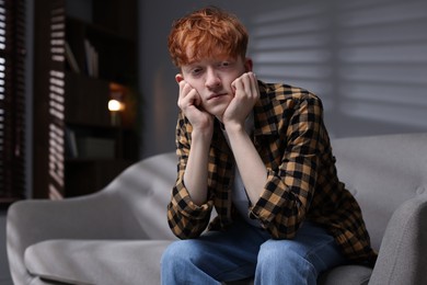 Photo of Teen problems. Depressed teenage boy on sofa at home