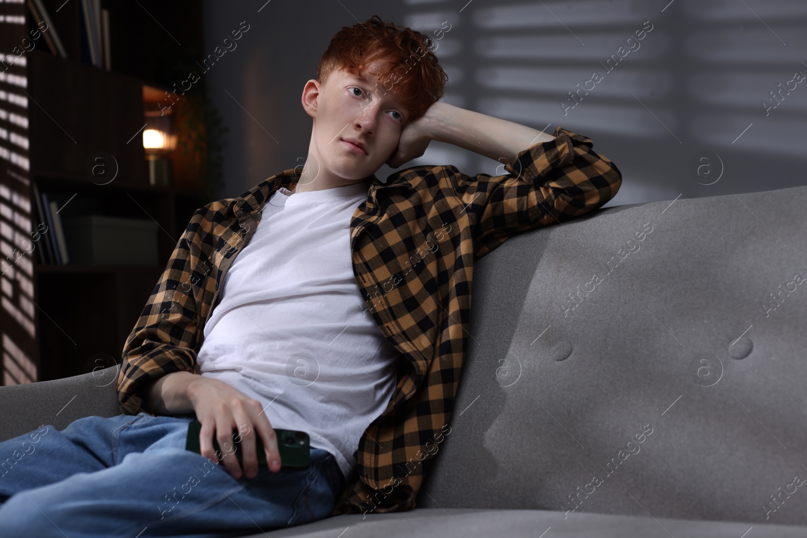 Teen problems. Depressed teenage boy with smartphone at home Photo of Teen problems. Depressed teenage boy with smartphone at home