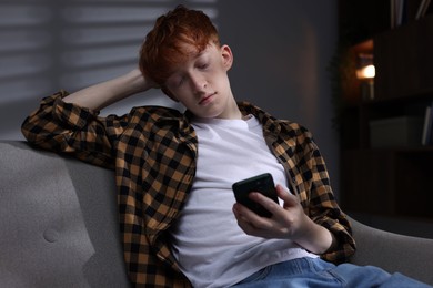 Photo of Teen problems. Depressed teenage boy with smartphone at home