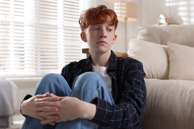 Photo of Teen problems. Depressed teenage boy on sofa at home
