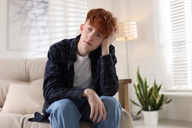 Photo of Teen problems. Depressed teenage boy on sofa at home