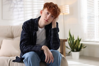 Photo of Teen problems. Depressed teenage boy on sofa at home