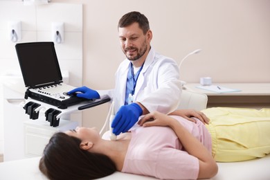 Photo of Sonographer conducting ultrasound examination of woman's thyroid gland in clinic