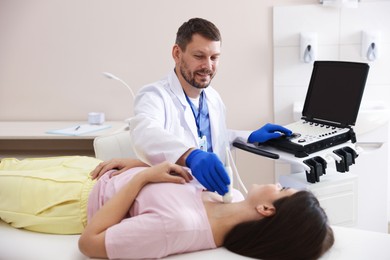 Photo of Sonographer conducting ultrasound examination of woman's thyroid gland in clinic