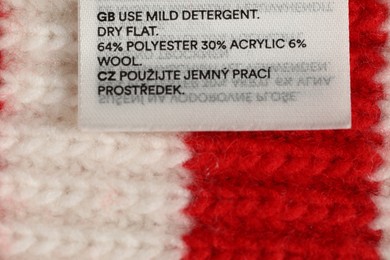 Photo of Clothing label on knitted garment as background, top view