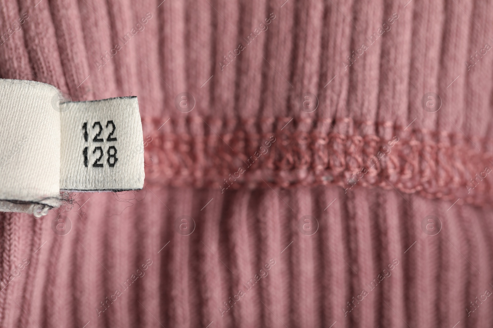 Photo of Clothing label with size on knitted garment as background, above view
