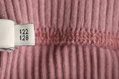 Photo of Clothing label with size on knitted garment as background, above view