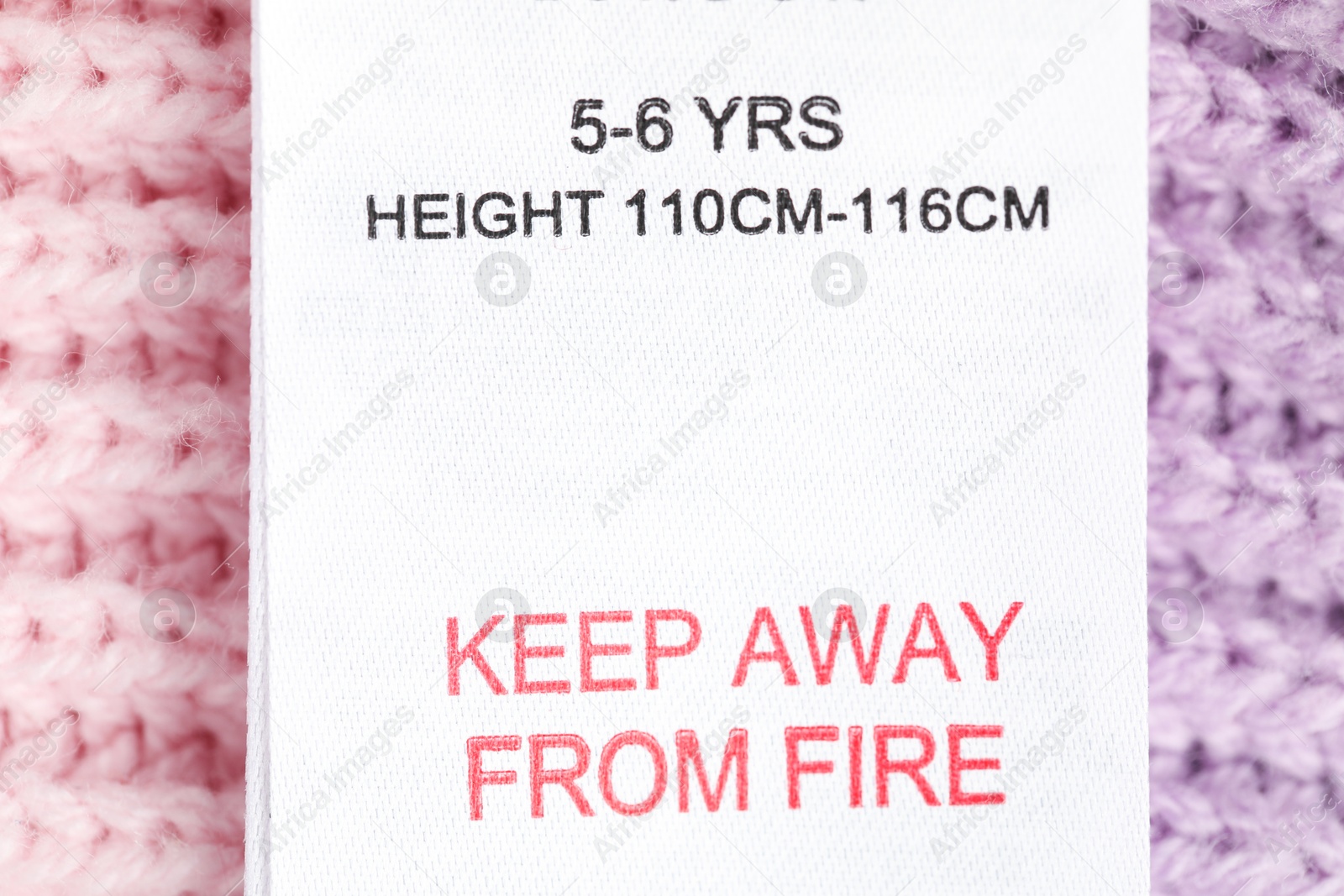 Clothing label with care advice and size on knitted garment as background, top view Photo of Clothing label with care advice and size on knitted garment as background, top view
