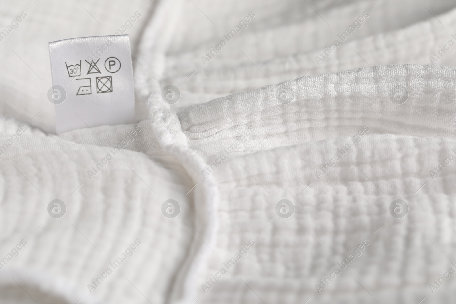 Clothing label with care symbols on white garment as background, closeup Photo of Clothing label with care symbols on white garment as background, closeup