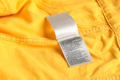 Photo of Clothing label on yellow garment as background, above view