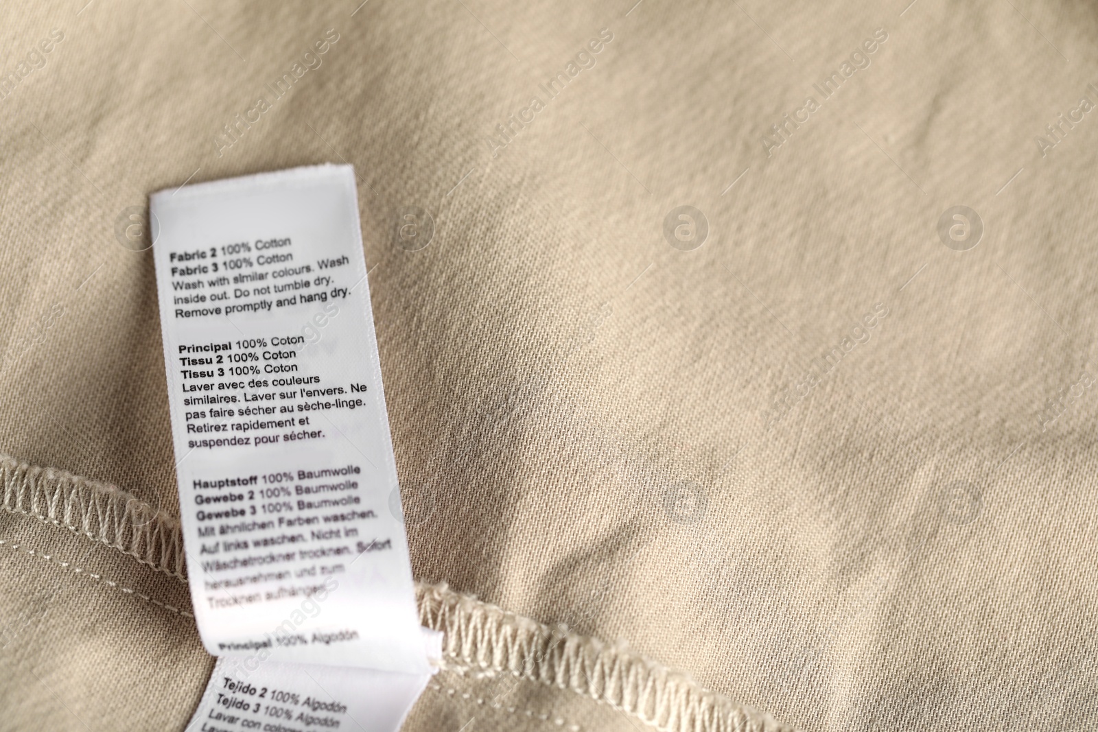 Photo of Clothing label on beige garment as background, above view
