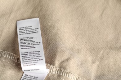 Photo of Clothing label on beige garment as background, above view