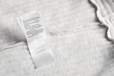 Photo of Clothing label on light garment as background, above view