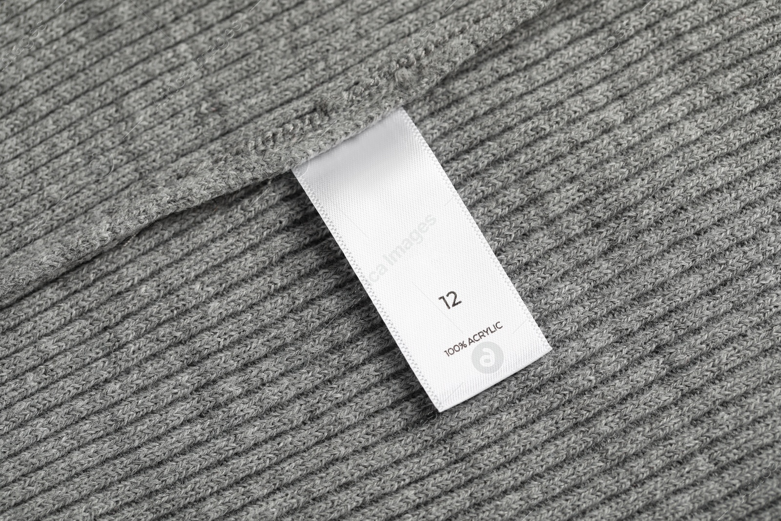 Clothing label with size and material content on grey garment as background, top view Photo of Clothing label with size and material content on grey garment as background, top view