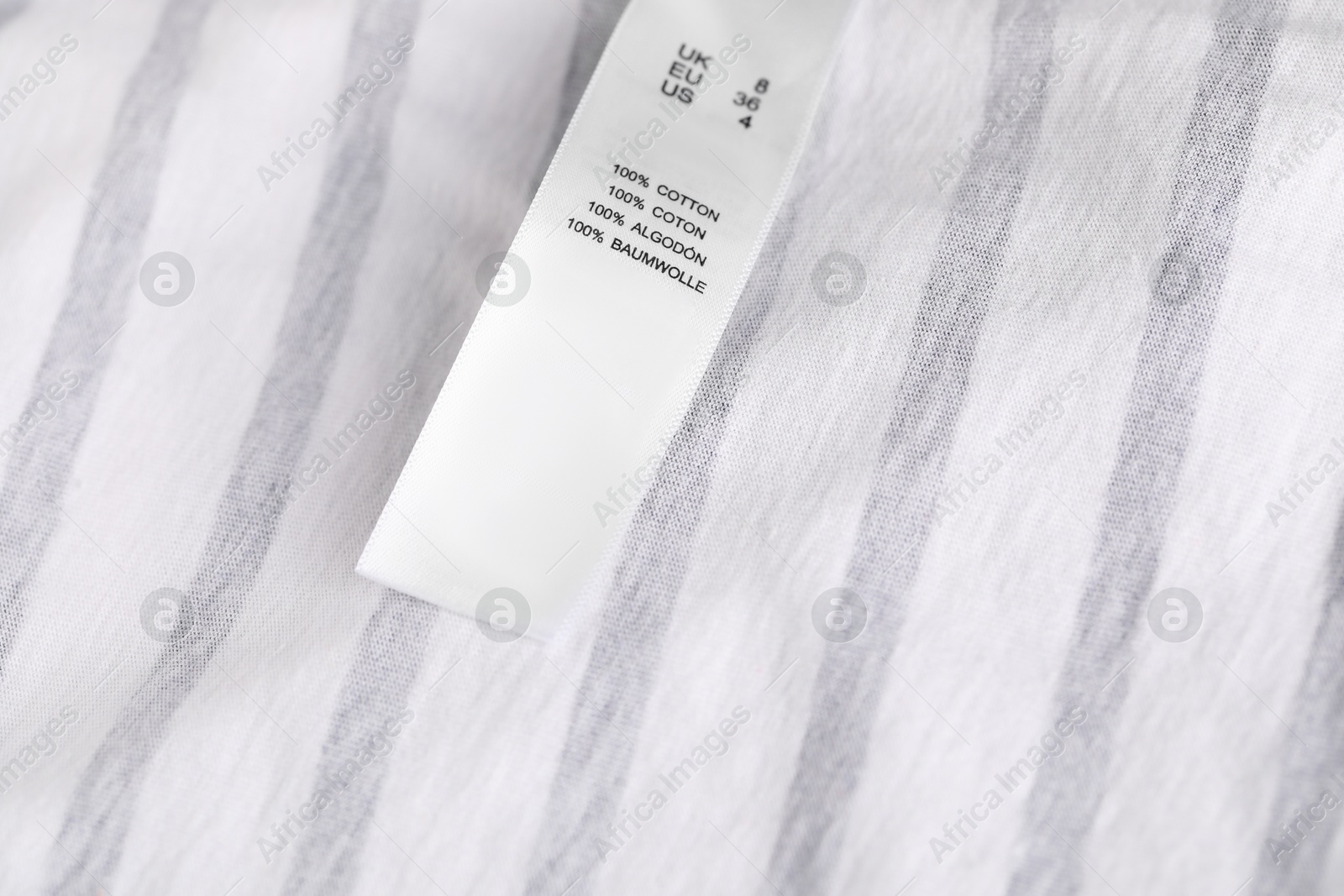 Clothing label with size and material content on striped garment as background, closeup Photo of Clothing label with size and material content on striped garment as background, closeup