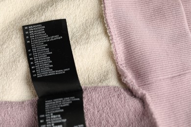 Photo of Clothing label with material content on color garment as background, above view