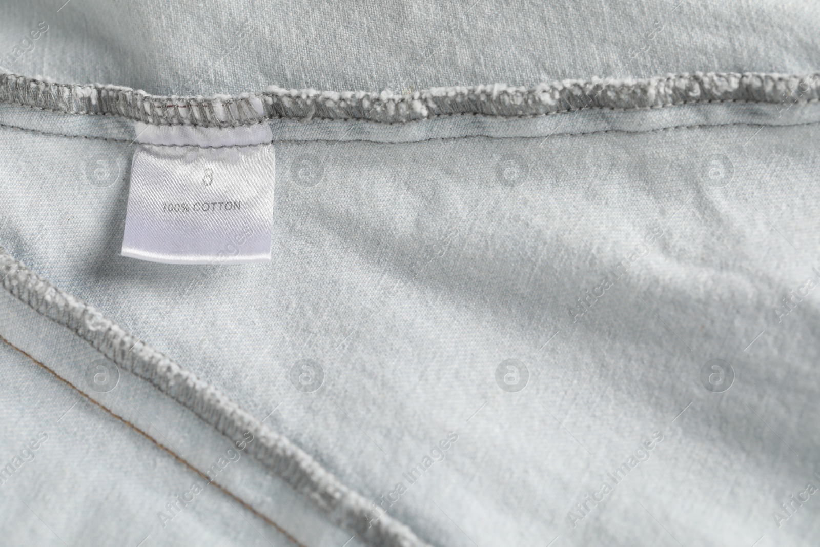 Clothing label with size and material content on garment as background, top view Photo of Clothing label with size and material content on garment as background, top view