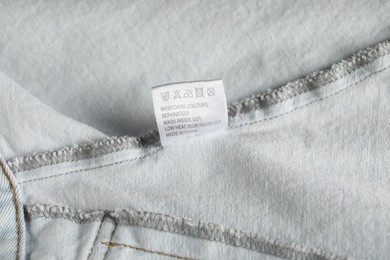 Photo of Clothing label with care symbols on garment as background, closeup