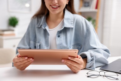 Photo of Woman using modern tablet at desk indoors, closeup