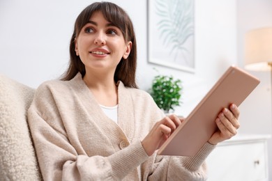 Photo of Woman using modern tablet in armchair at home