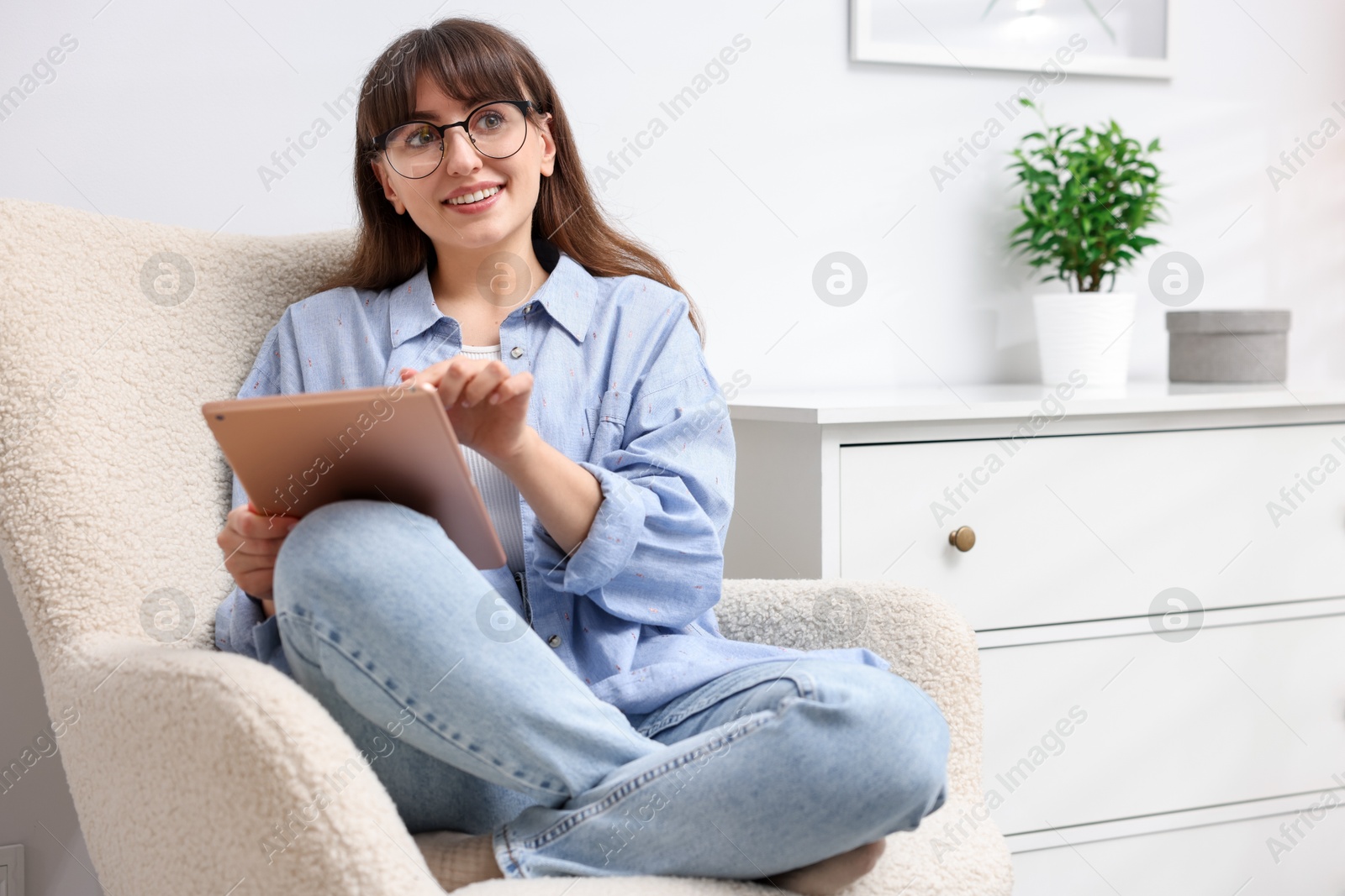 Photo of Woman using modern tablet in armchair at home. Space for text